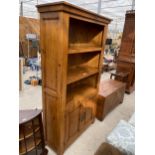 A MODERN OAK OPEN DISPLAY UNIT WITH THREE TIERS, HAVING TWO PANELLED DOORS TO THE ASE, WITH