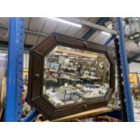 AN OAK FRAMED ARTS AND CRAFTS STYLE MIRROR IN AN OCTAGONAL SHAPE WITH BEVELLED GLASS