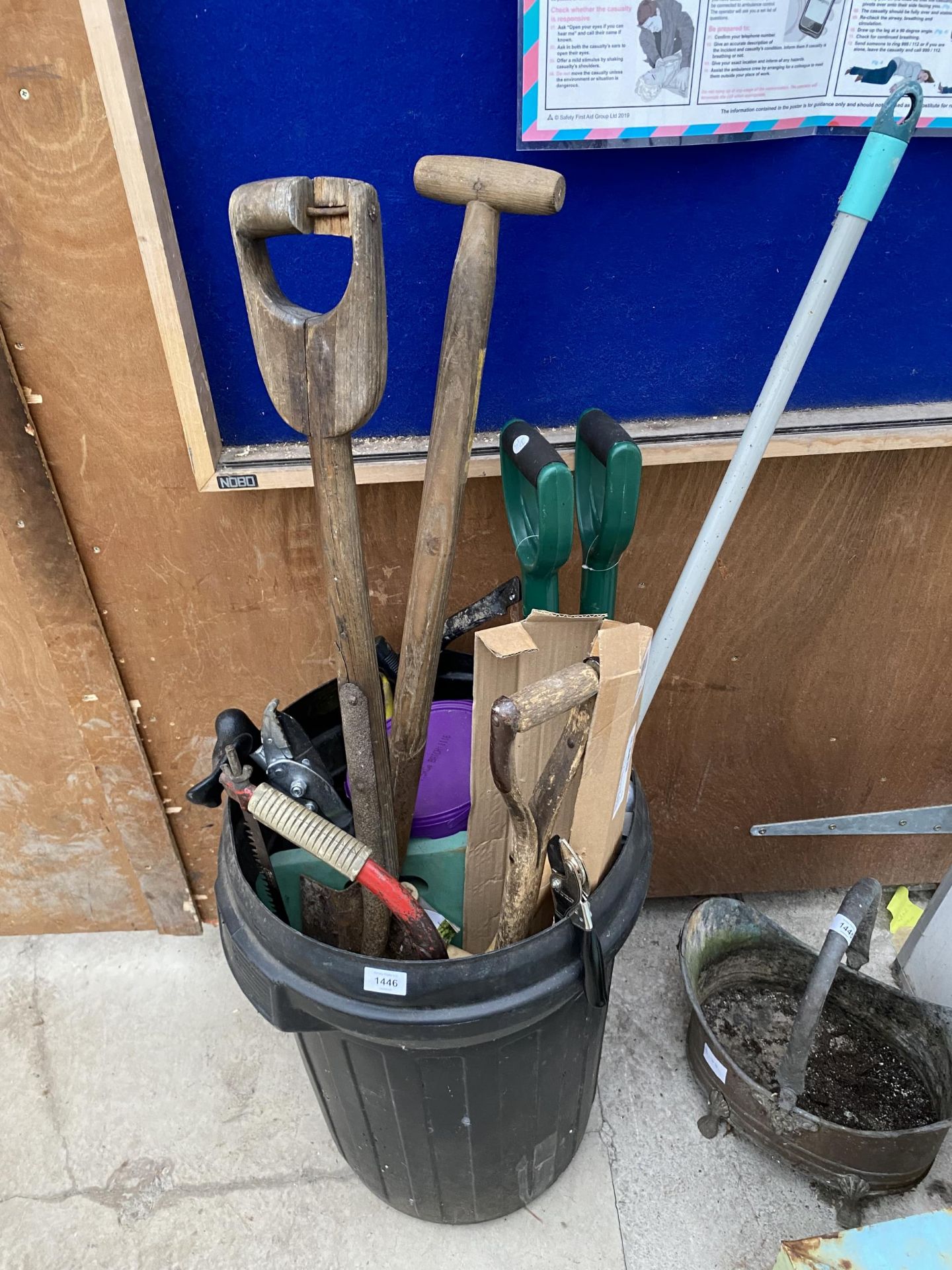 A DUSTBIN CONTAINING A LARGE QUANTITY OF TOOLS TO INCLUDE SAWS AND SPADES ETC