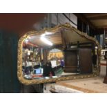 A VINTAGE BEVELLED GLASS WALL MIRROR WITH ORNATE GILDED FRAME