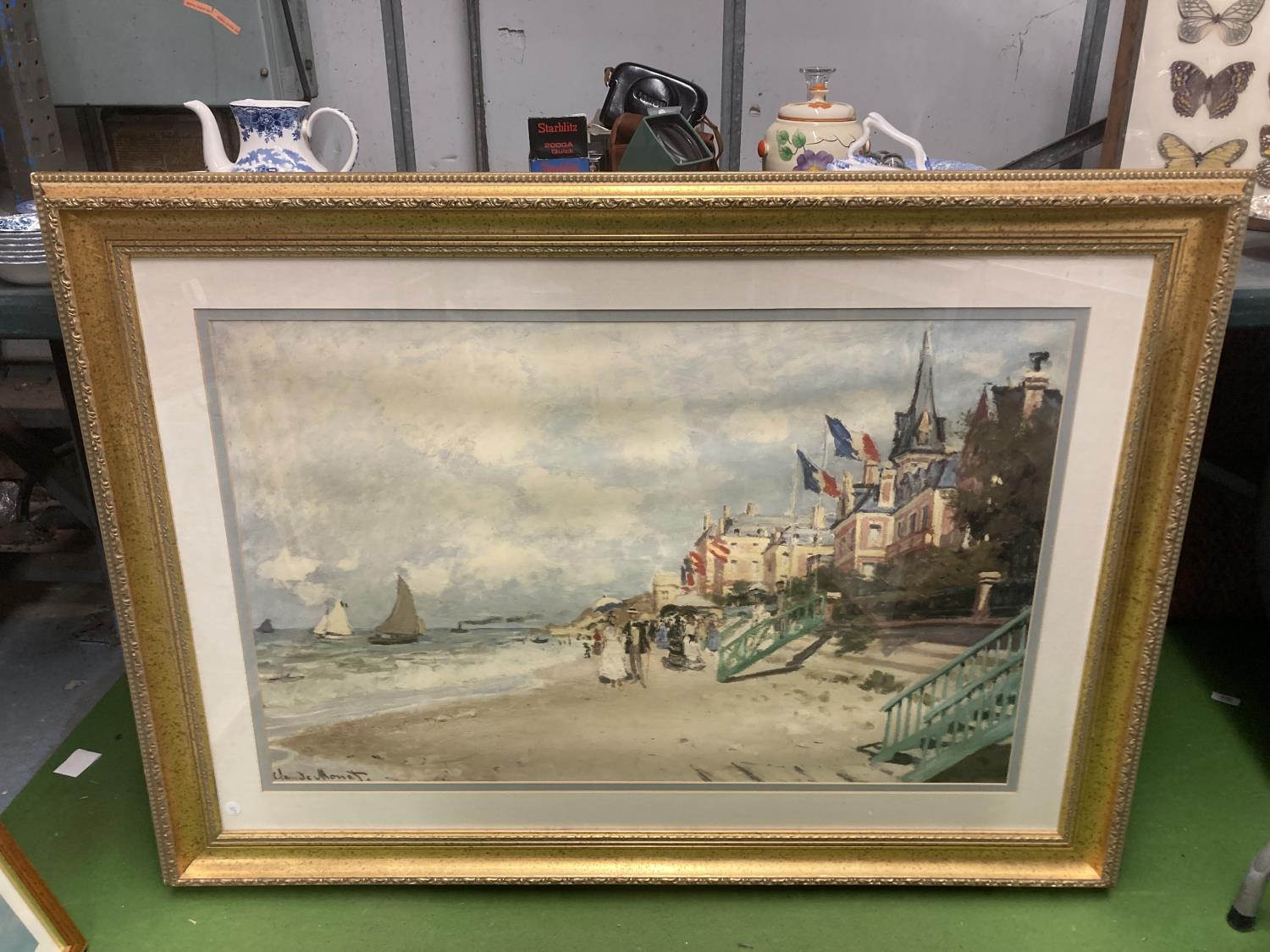 A GILT FRAMED CLAUDE MONET PRINT - 'THE BOARDWALK AT TROUVILLE' 119CM X 87CM