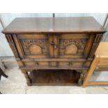 AN OAK JACOBEAN STYLE COCKTAIL CABINET WITH PANELLED DOOR, PULL OUT SLIDE, TWO DRAWERS AND A POT