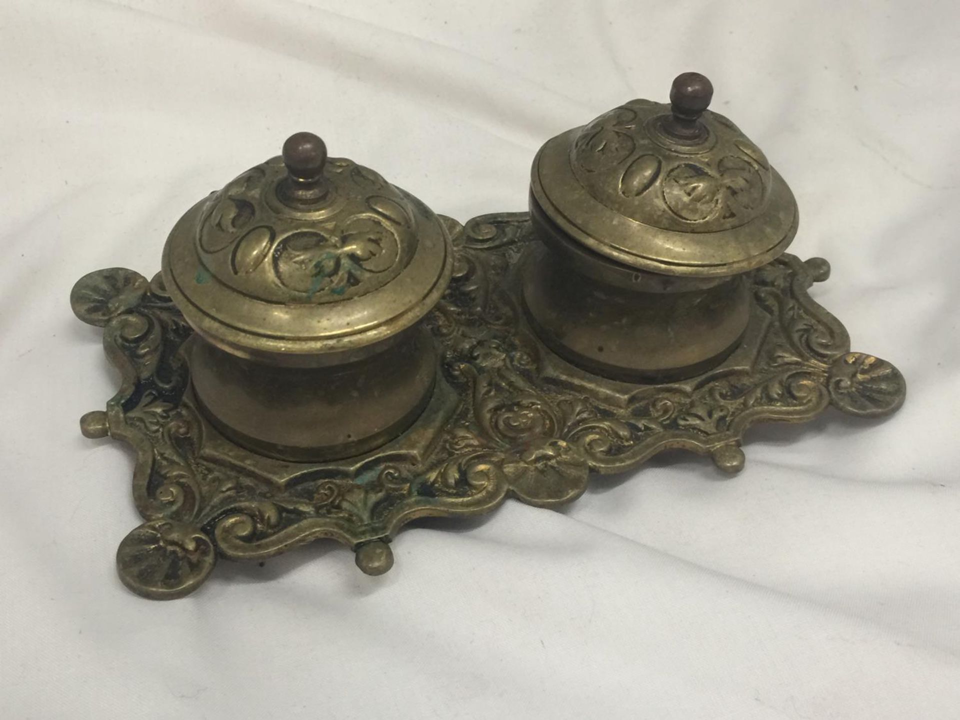 A VINTAGE BRASS INKWELL WITH ORNATE DECORATION INCLUDING ONE LINER