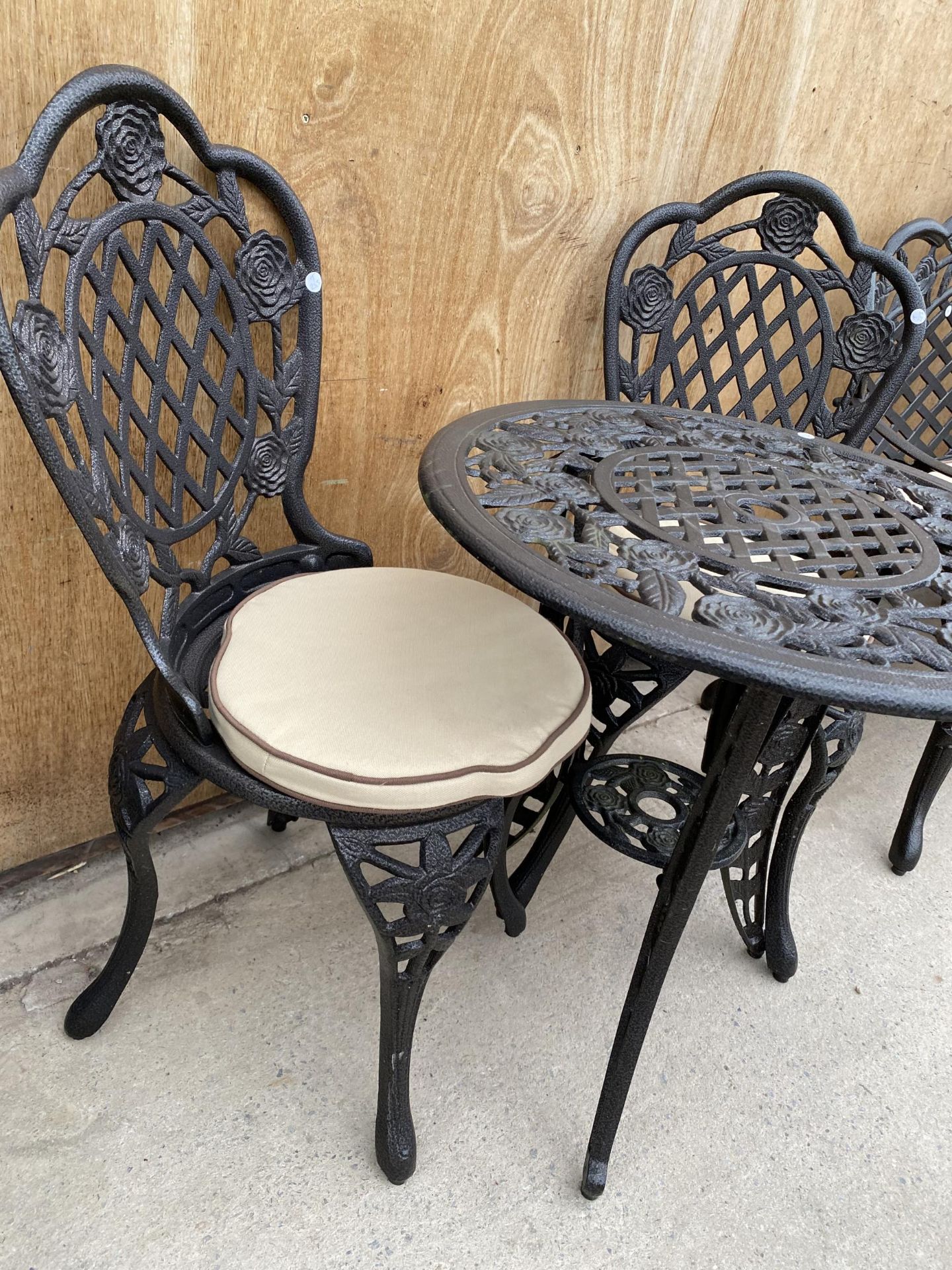 A CAST ALLOY BISTRO SET COMPRISING OF A ROUND FLORAL TABLE AND TWO CHAIRS WITH CUSHIONS - Image 2 of 3