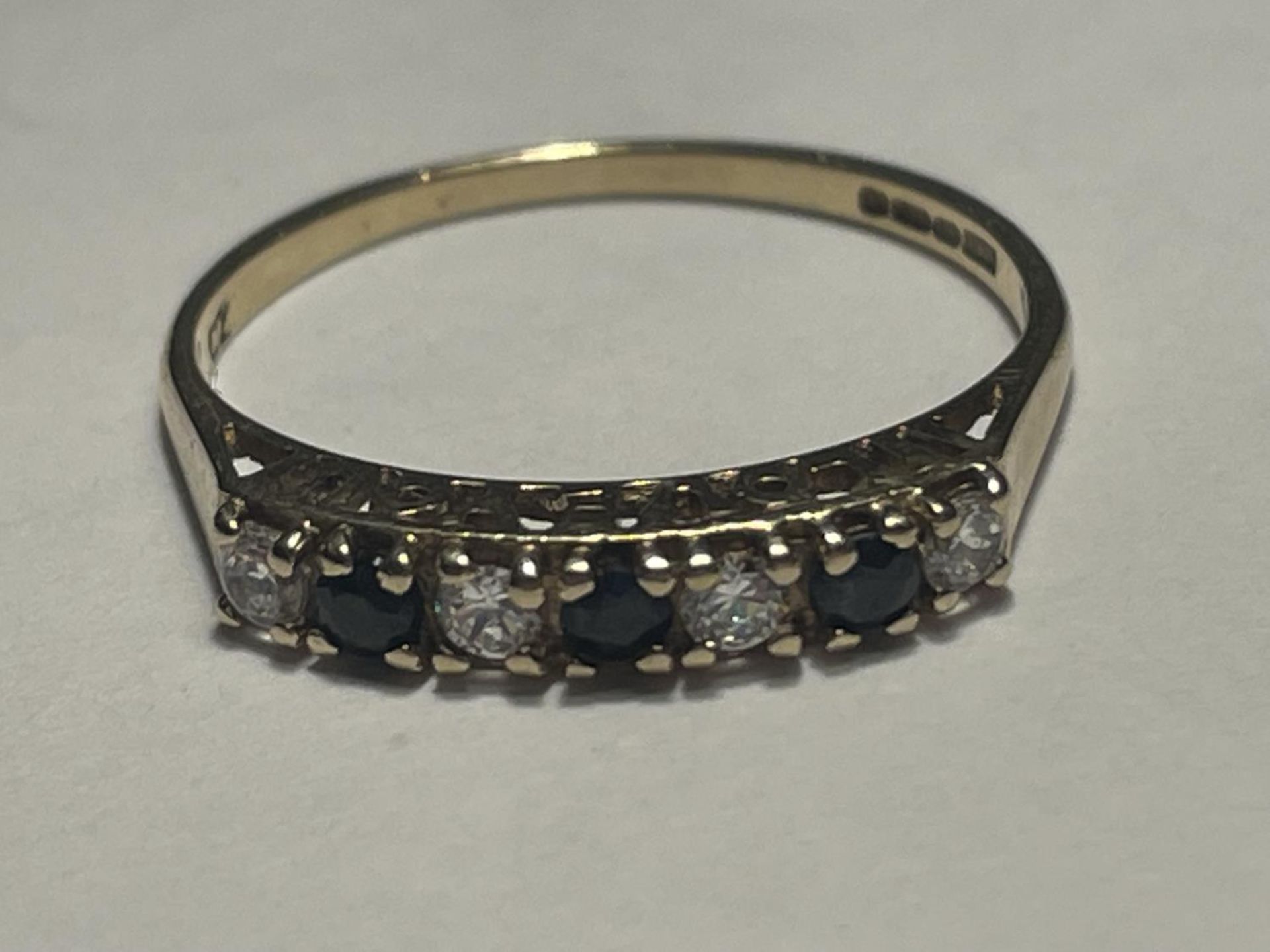 A 9 CARAT GOLD RING WITH THREE SAPPHIRES AND FOUR CUBIC ZIRCONIAS IN A LINE SIZE P
