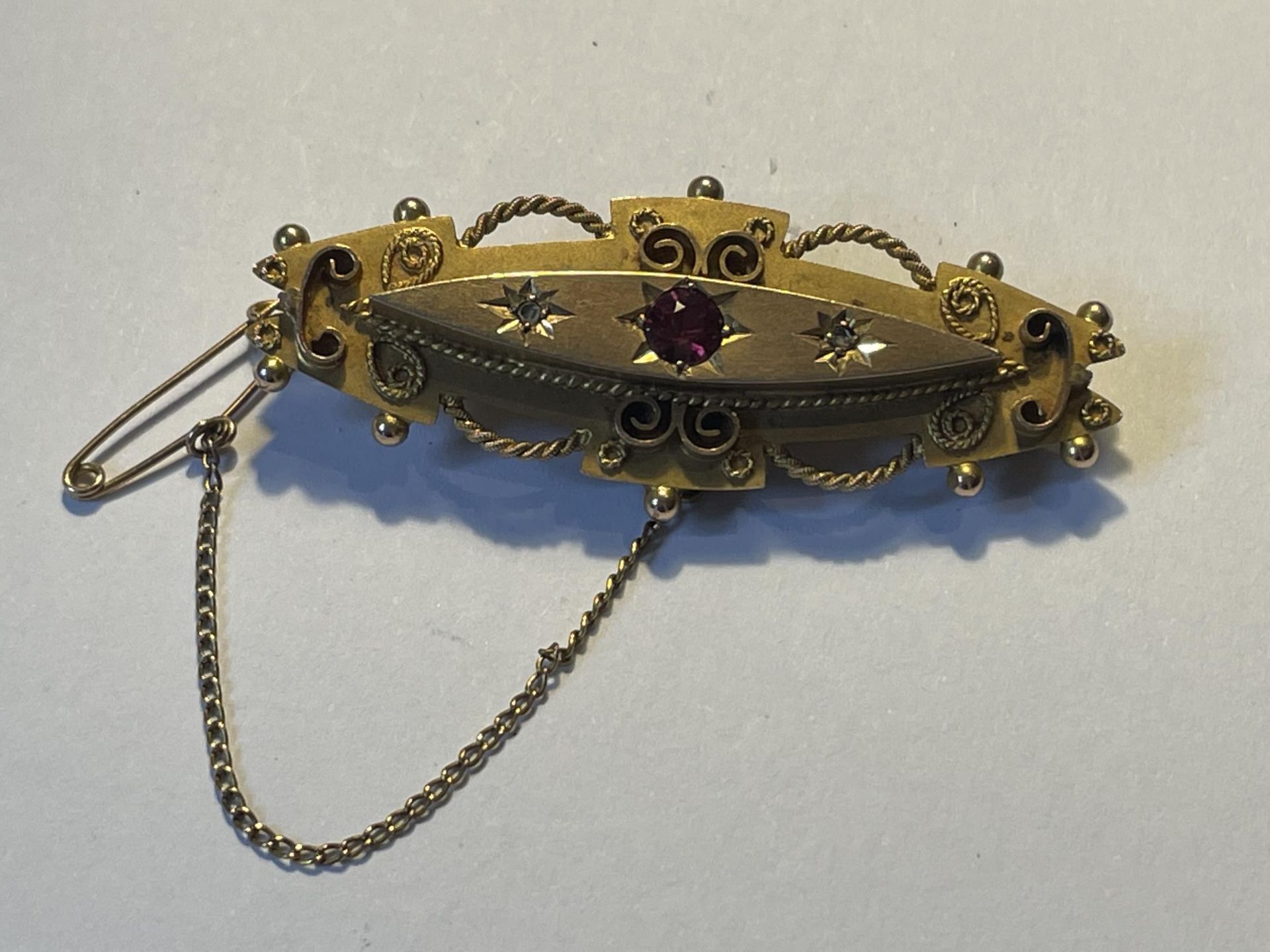 A 9 CARAT GOLD BROOCH WITH A RED STONE GROSS WEIGHT 5.11 GRAMS