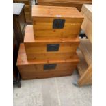 A MODERN SET OF THREE GRADUATED PINE CHESTS WITH METALWARE HANDLES AND CLASPS