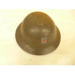 A GREEN PAINTED METAL BRODIE HELMET AND LINER