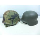 A PAINTED METAL GERMAN HELMET AND A CAMOUFLAGE COVERED HELMET