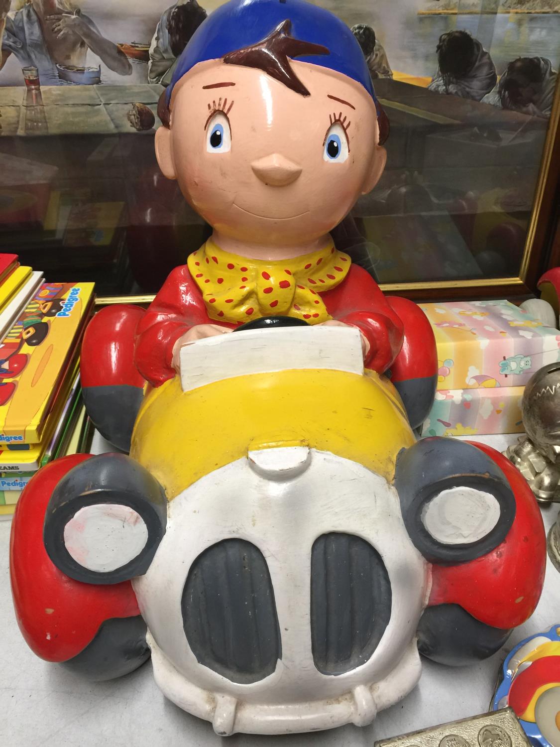 A HARD PLASTIC NODDY IN HIS CAR MODEL CHARITY MONEY BOX MISSING HIS HAT AND THE BASE - 32 CM WIDE