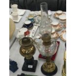 TWO OIL LAMPS TO INCLUDE A BRASS BASED ONE WITH GLASS MIDDLE AND CHIMNEY PLUS A BLACK CERAMIC