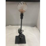 A BLACK TABLE LAMP WITH A THIN STEM AND AN EDISON TYPE BULB