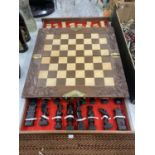 A CHESS SET WITH A WOOD AND RESIN TOP AND WOODEN CHESS PIECES CONTAINED IN DRAWERS, WITH BRASS