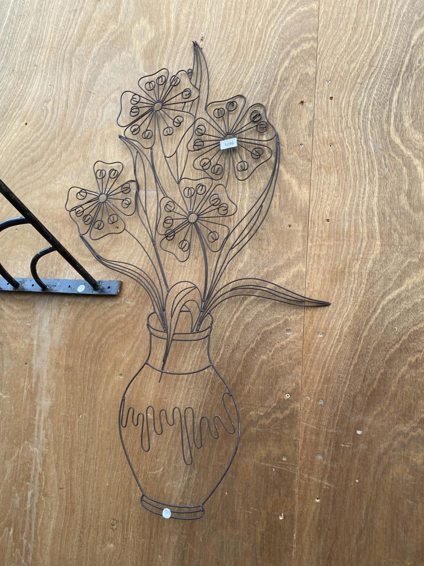 A BENT METAL WALL HANGING OF A VASE OF FLOWERS