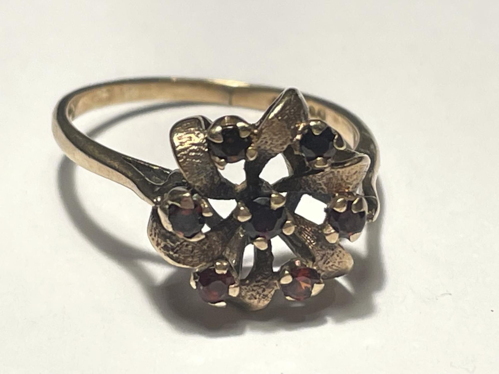 A 9 CARAT GOLD RING SET WITH SEVEN GARNETS SIZE O