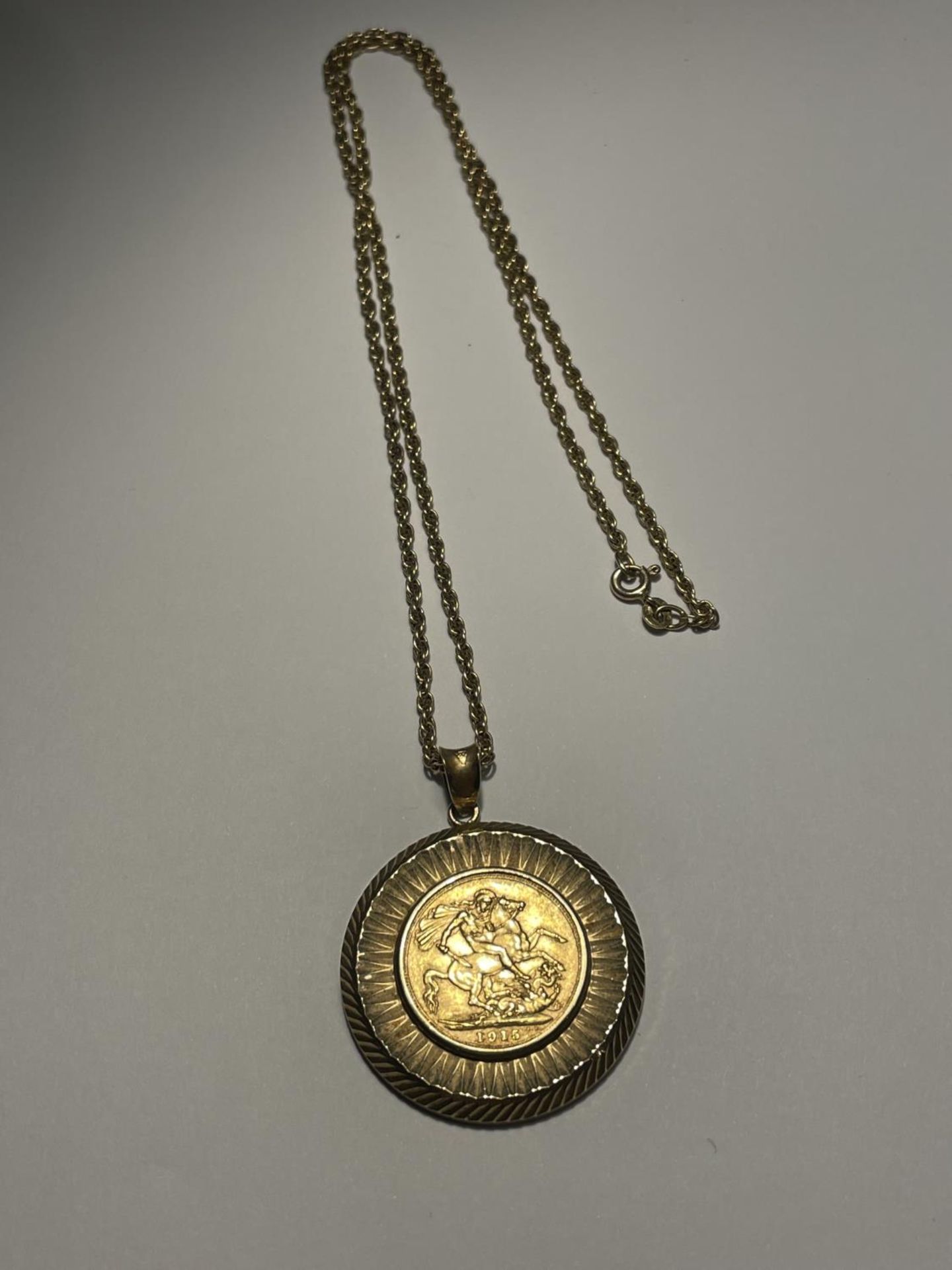 A 1915 GOLD SOVEREIGN IN A 9 CARAT GOLD MOUNT WITH A 9 CARAT GOLD CHAIN GROSS WEIGHT 19.78 GRAMS