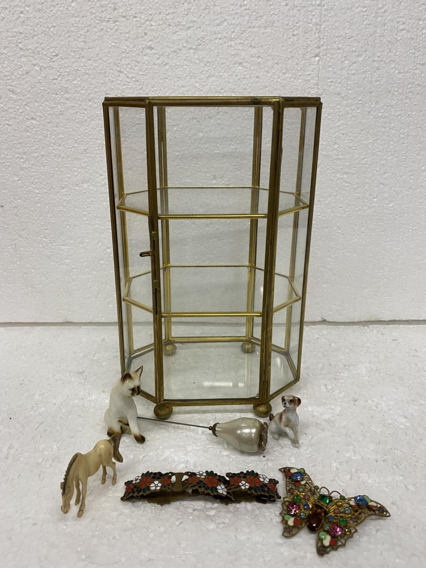 A BRASS AND GLASS SMALL DISPLAY CABINET WITH CONTENTS TO INCLUDE MINIATURE ANIMALS, A BRACELET,