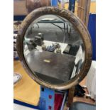 AN OVAL FRAMED MIRROR