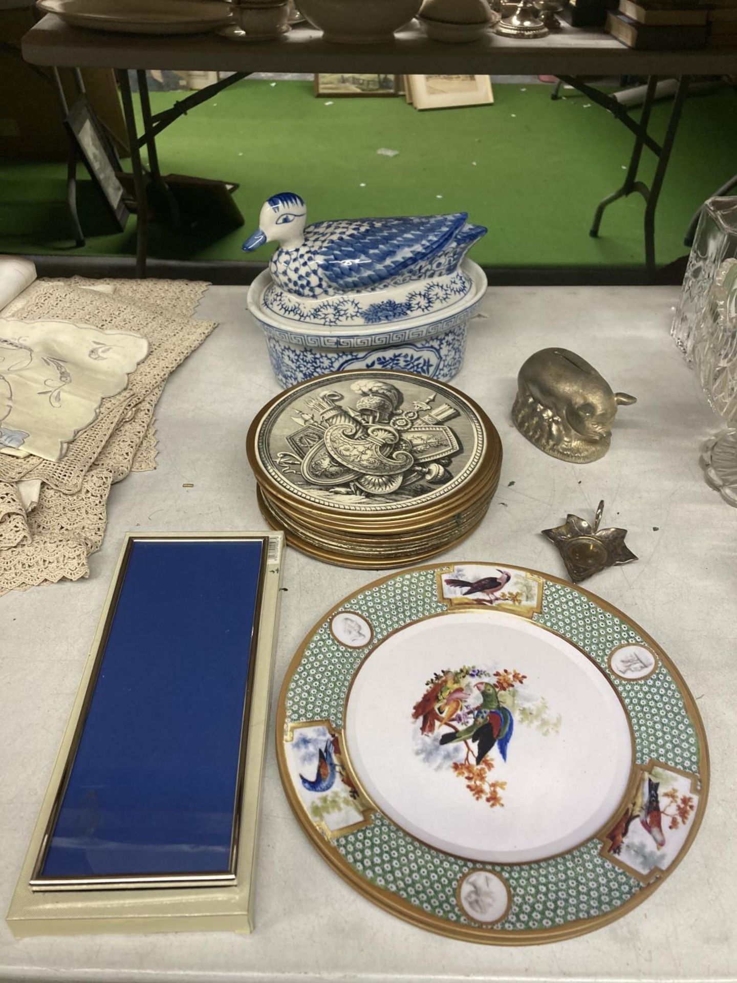 A MIXED LOT TO INCLUDE A BLUE AND WHITE TUREEN WITH A DUCK LID, ARMORIAL PLACE MATS, PIGGY BANK, ETC