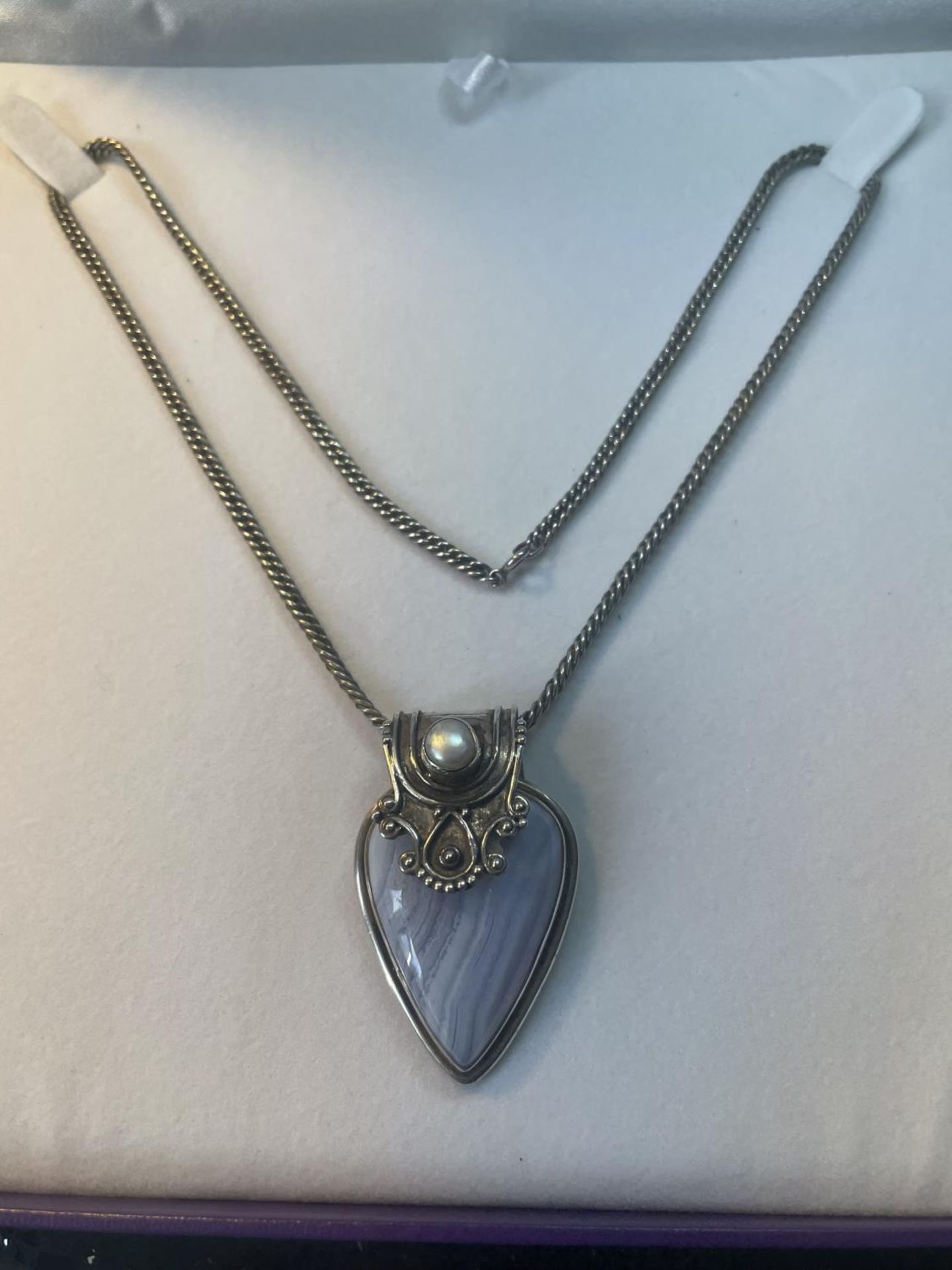 A MARKED SILVER NECKLACE WITH AN ORNATE FRAMED BLUE STONE PENDANT