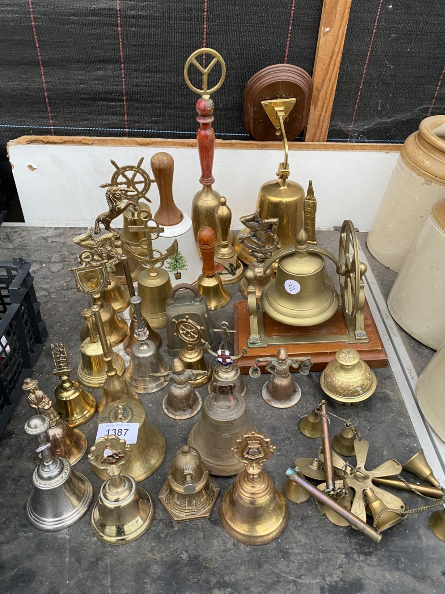 A LARGE QUANTITY OF BRASS HAND BELLS TO INCLUDE A BRASS SHIPS BELL WITH WOODEN PLINTH AND PULLEY