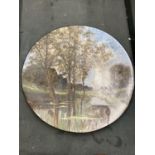 A LARGE CERAMIC WALL PLATE WITH A RIVER SCENE - SIGNED DIAMETER 33CM
