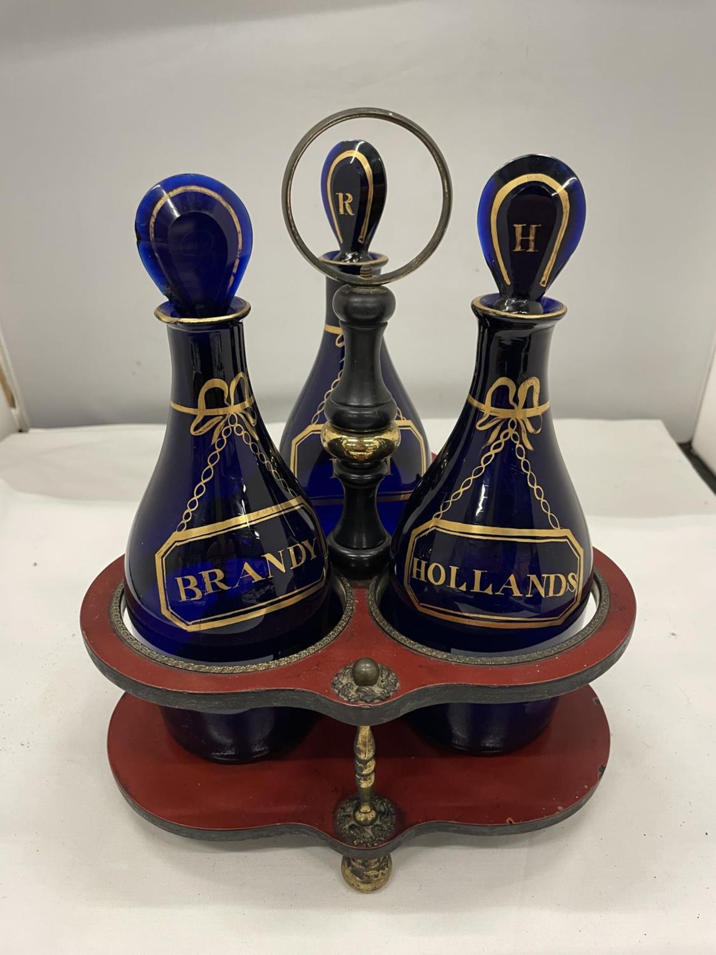 A SET OF THREE GEORGE III GILDED BRISTOL BLUE GLASS DECANTERS IN BRASS AND LAQUERED FRAME