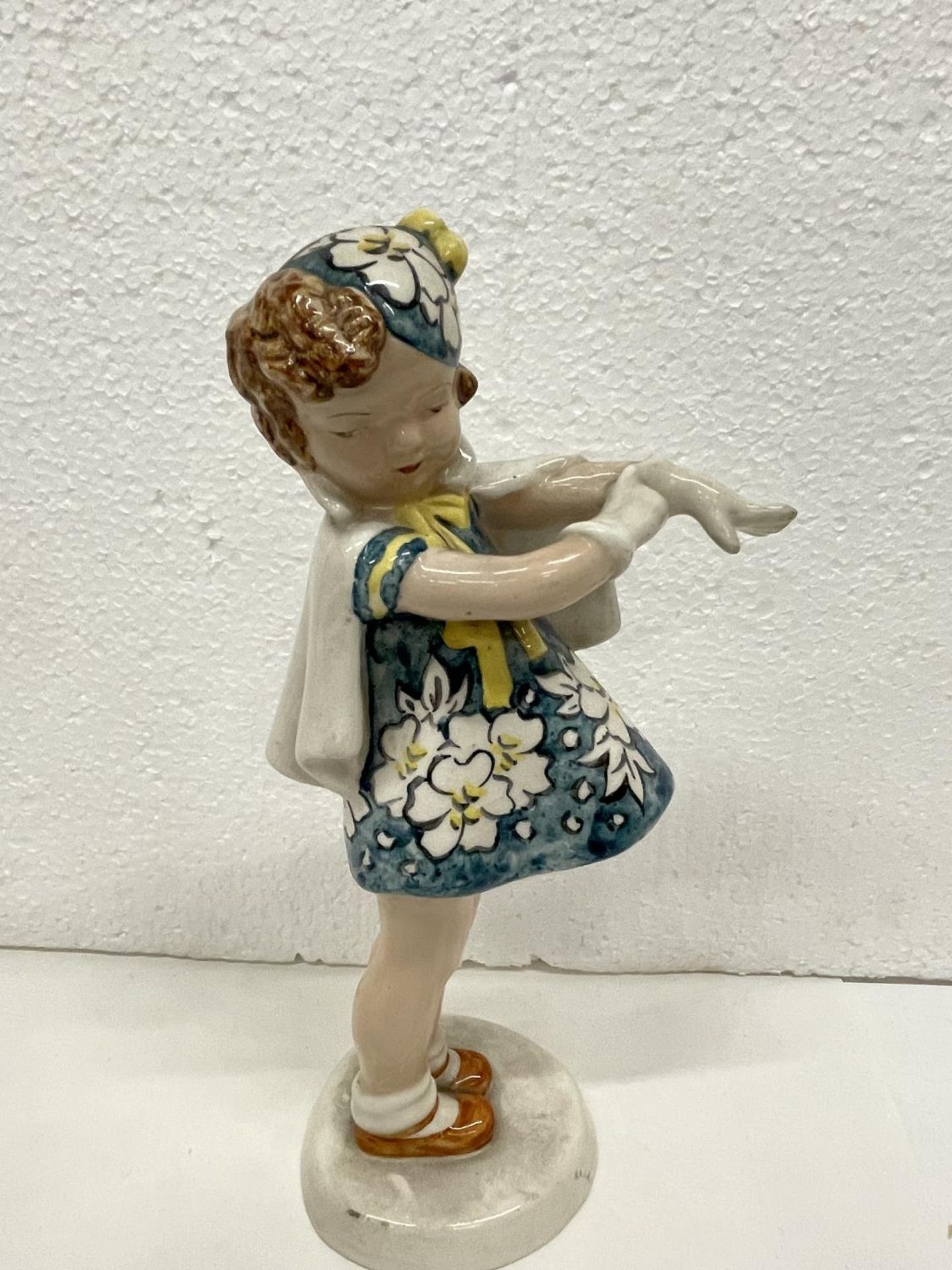 A GOLDSHIEIDER FIGURE OF GIRL PUTTING ON GLOVES HEIGHT 23CMS