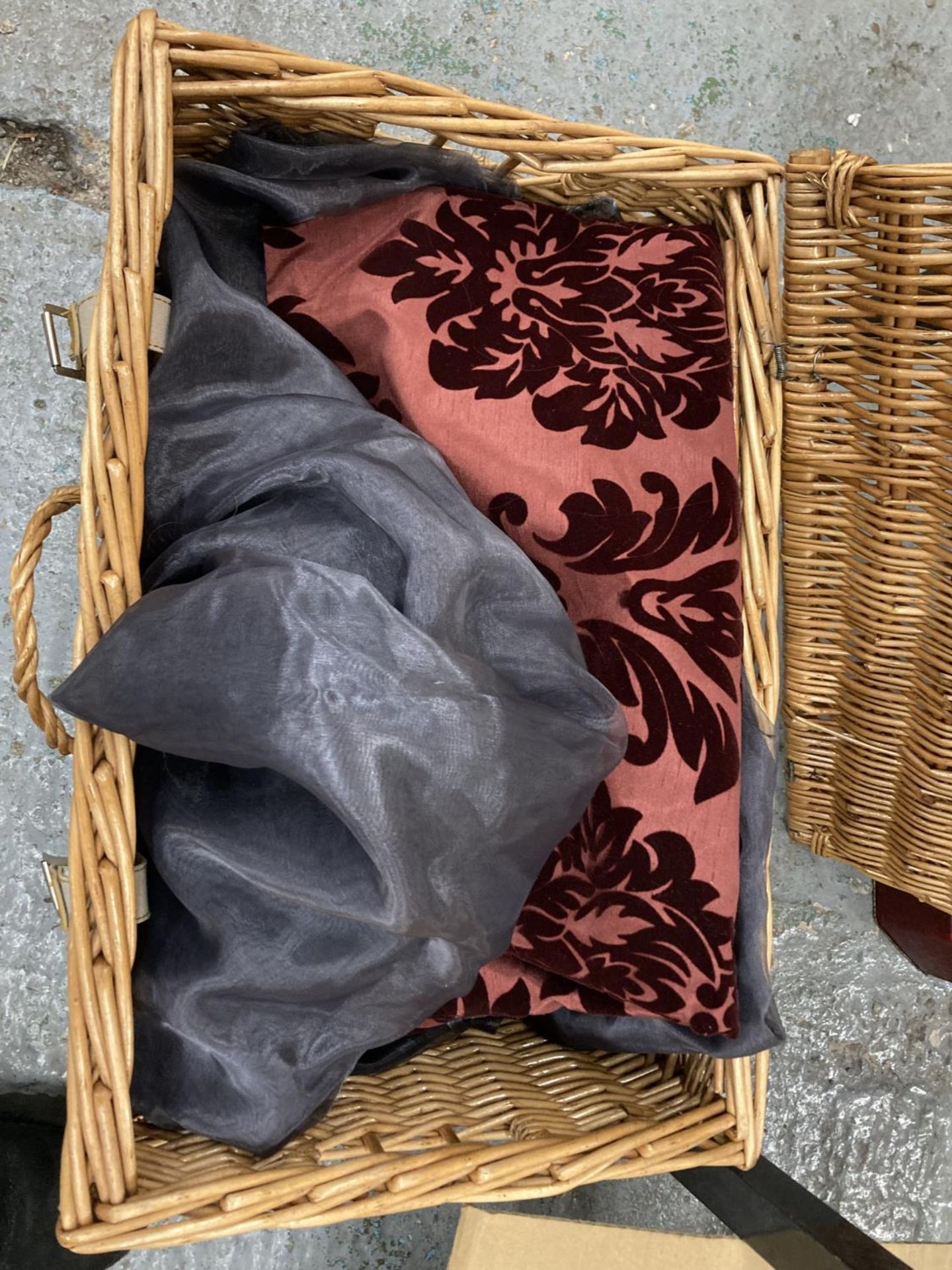 A WICKER PICNIC BASKET CONTAINING MATERIAL