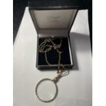 A YELLOW METAL CHAIN WITH A DECORATIVE MAGNIFYING GLASS PENDANT IN A PRESENTATION BOX