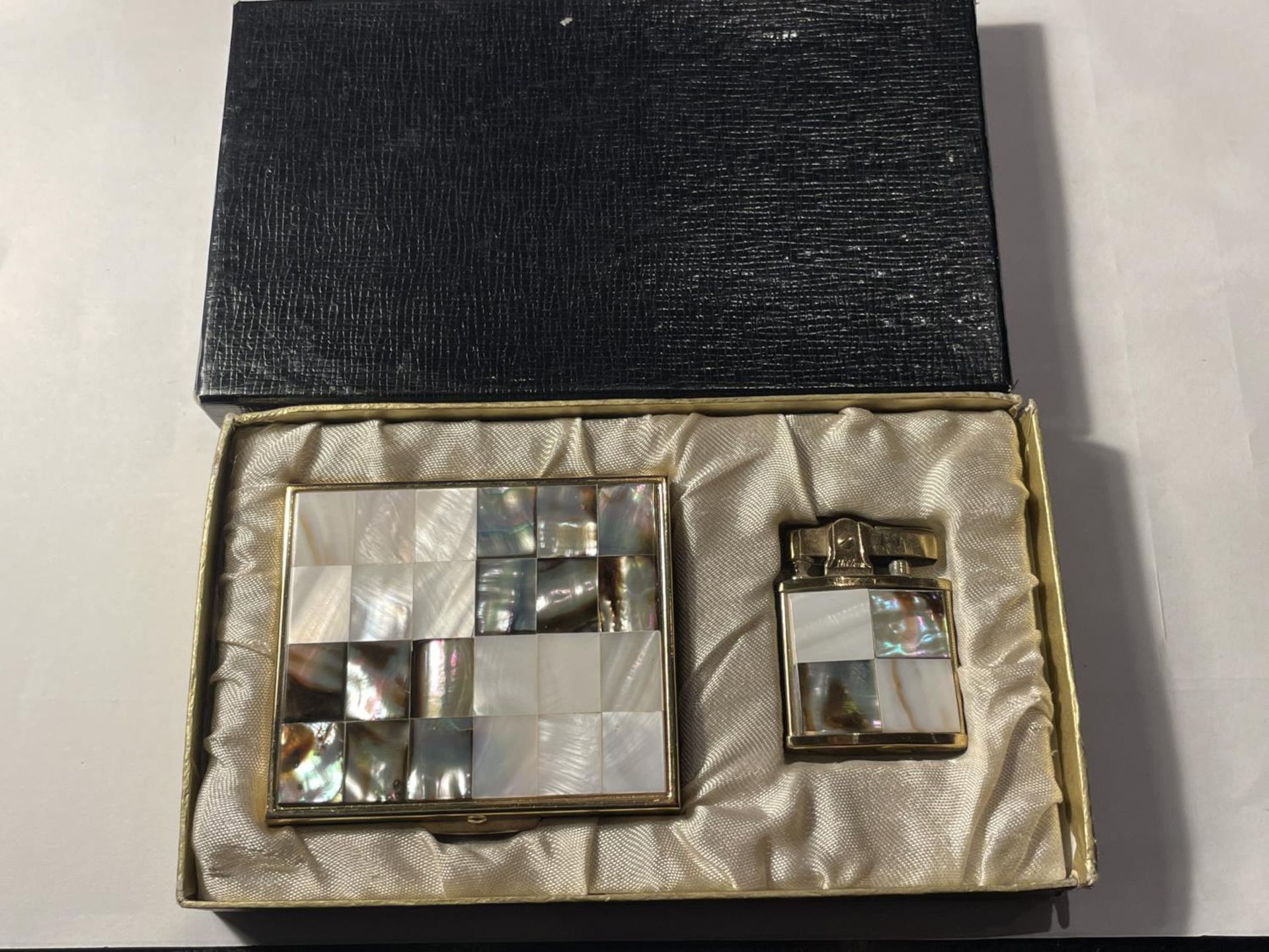 A VINTAGE BOXED SET COMPRISING OF A MOTHER OF PEARL HILTON LIGHTER AND A MATCHING MIRRORED COMPACT