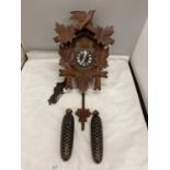 A WOODEN CUCKOO CLOCK WITH PENDULUM AND CARVED LEAVES AND BIRD