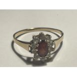 A 9 CARAT GOLD RING WITH A CENTRE RED STONE SURROUNDED BY TEN CUBIC ZIRCONIAS SIZE R