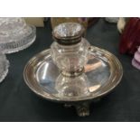 A CUT GLASS AND SILVER PLATED INKWELL FIXED TO A TRAY ON THREE DECOTTIVE FEET