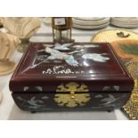 AN ORIENTAL STYLE MUSICAL JEWELLERY BOX WITH CRIMSON LACQUER AND MOTHER OF PEARL STORK DECORATION