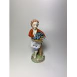 A CONTINENTAL 'DRESDEN' PORCELAIN MODEL OF A BOY HOLDING A BASKET OF FLOWERS