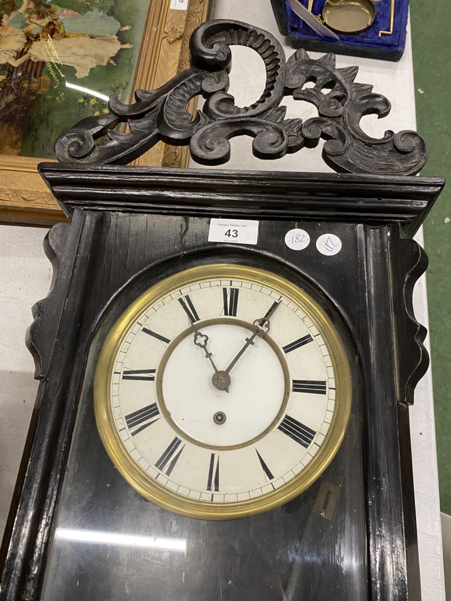 A LARGE WALL CLOCK IN EBONISED CASE WITH CARVED TOP WITH PENDULUM AND WEIGHT - Image 2 of 2