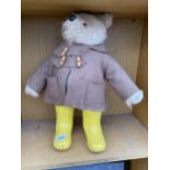 A VINTAGE TEDDY BEAR WEARING A RAIN COAT AND YELLOW WELLINGTON BOOTS