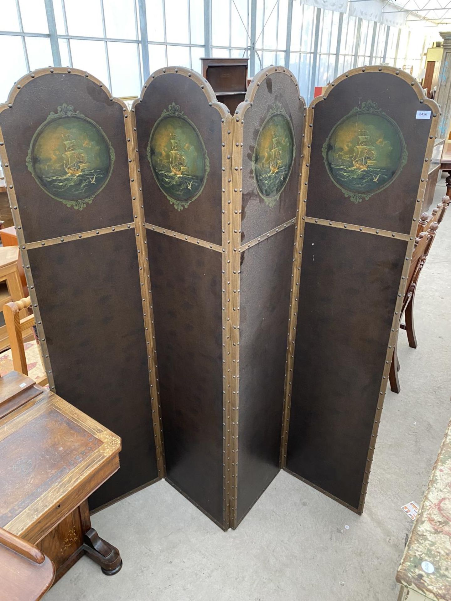 AN EDWARDIAN FOUR DIVISION STUDDED LEATHERETTE SCREEN WITH ARCHED TOPS HAVING PAINTED MASTED SHIP