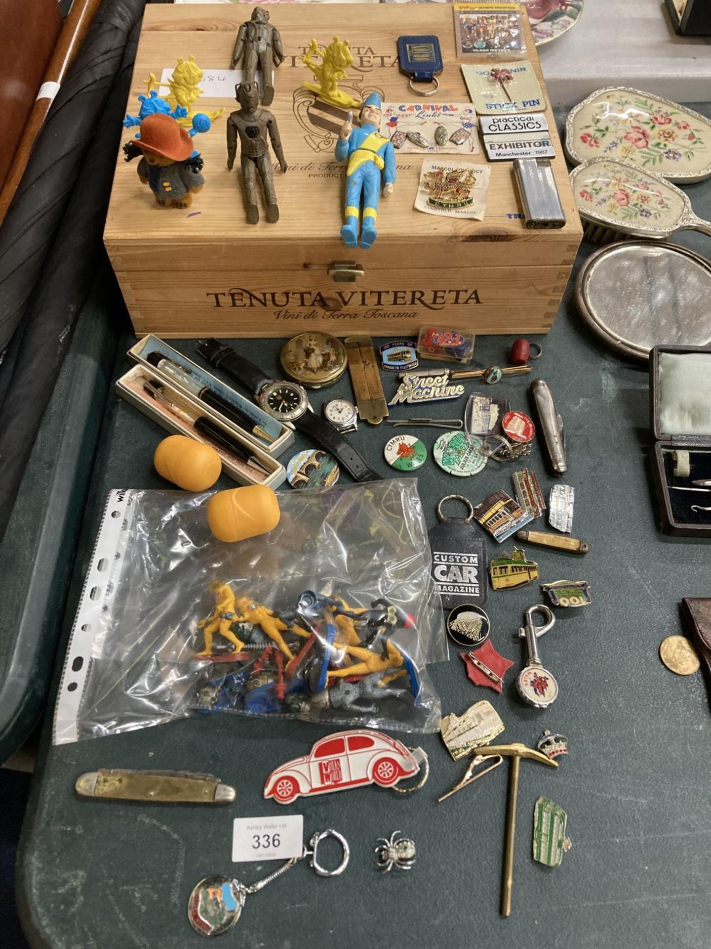 A CIGAR BOX CONTAINING A QUANTITY OF ITEMS TO INCLUDE ACTION FIGURES, BADGES, WATCHES, KEYRINGS,