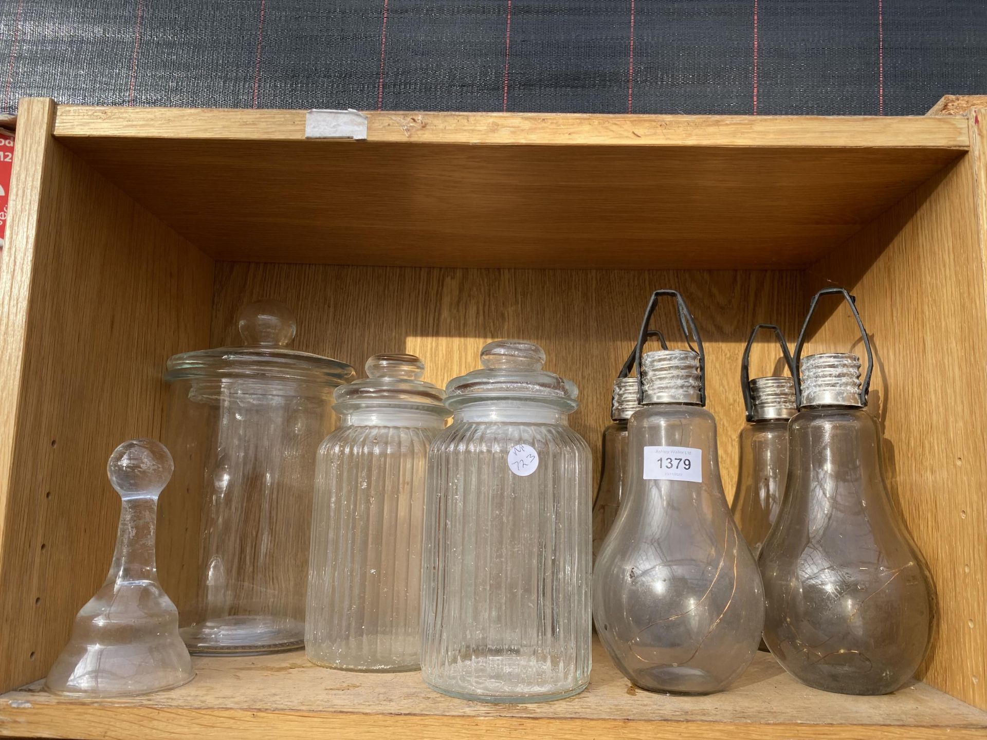AN ASSORTMENT OF GLASS STORAGE JARS AND GLASS LIGHTS IN THE FORM OF A LIGHT BULB ETC