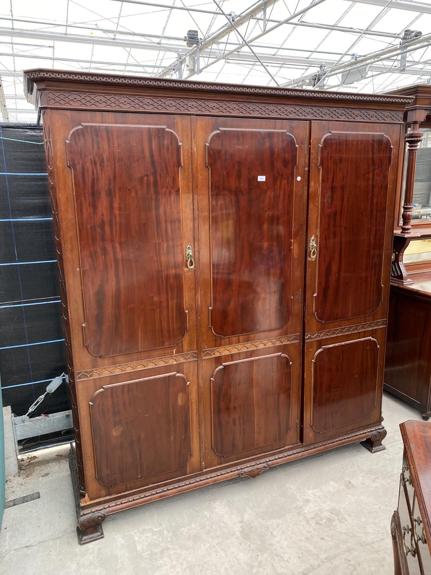 AN EDWARDIAN MAHOGANY 'CHIPPENDALE' STYLE TRIPLE WARDROBE ENCLOSING HANGING COMPARTMENTS, FIVE