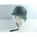 A GREEN PAINTED GERMAN METAL HELMET AND LINER