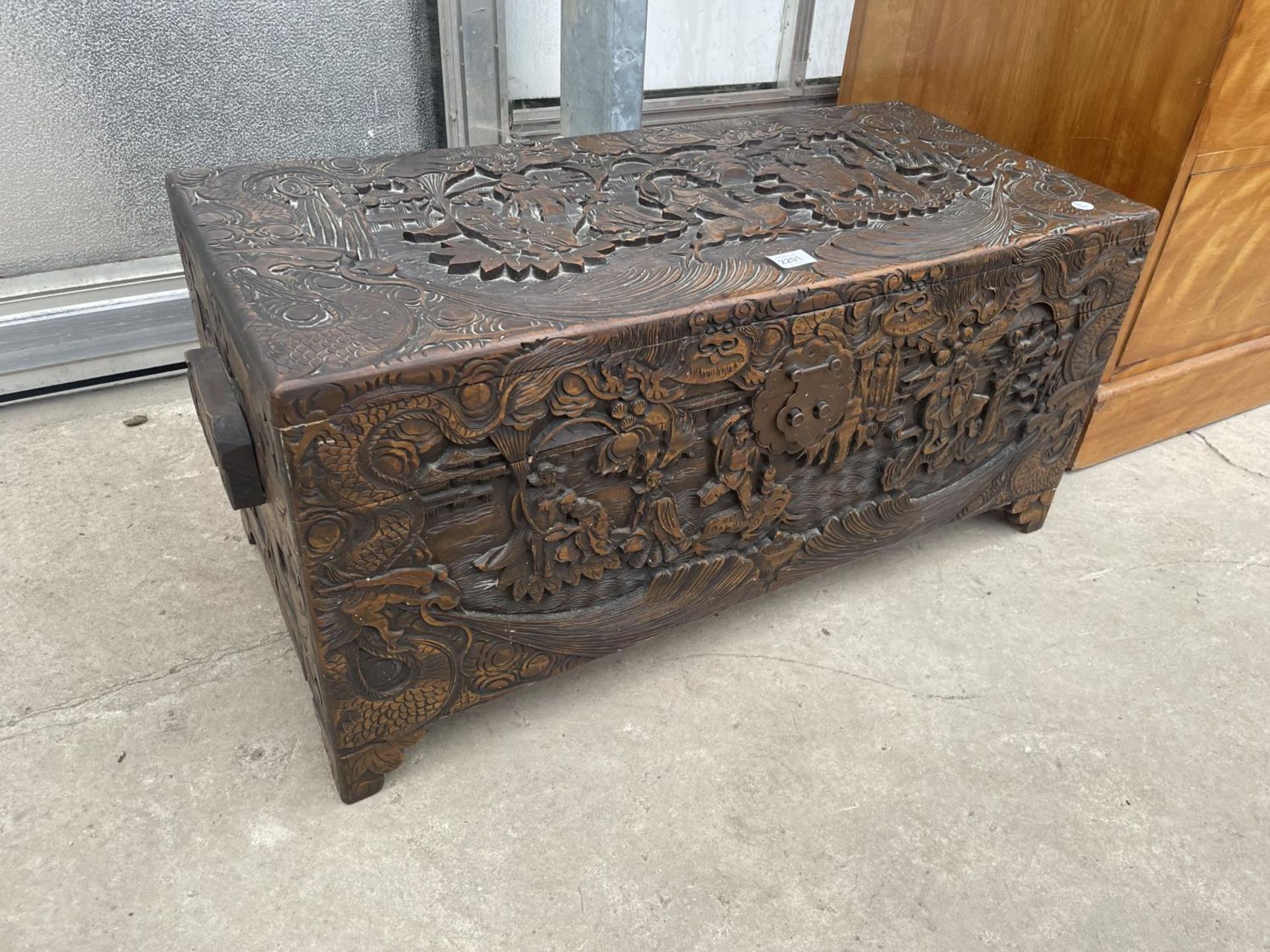 A MID 20TH CENTURY CAMPHOR WOOD CHEST PROFUSELY CARVED WITH ORIENTAL SCENES, 31.5X14.5"