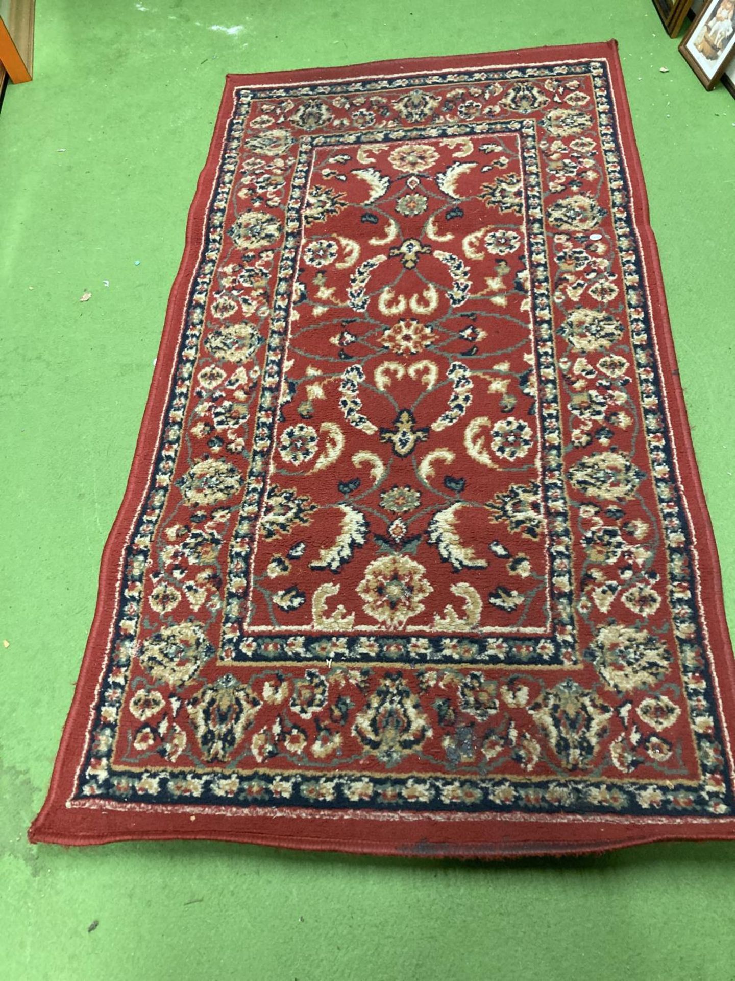 A RED WOOLLEN PATTERNED RUG 150CM X 79CM