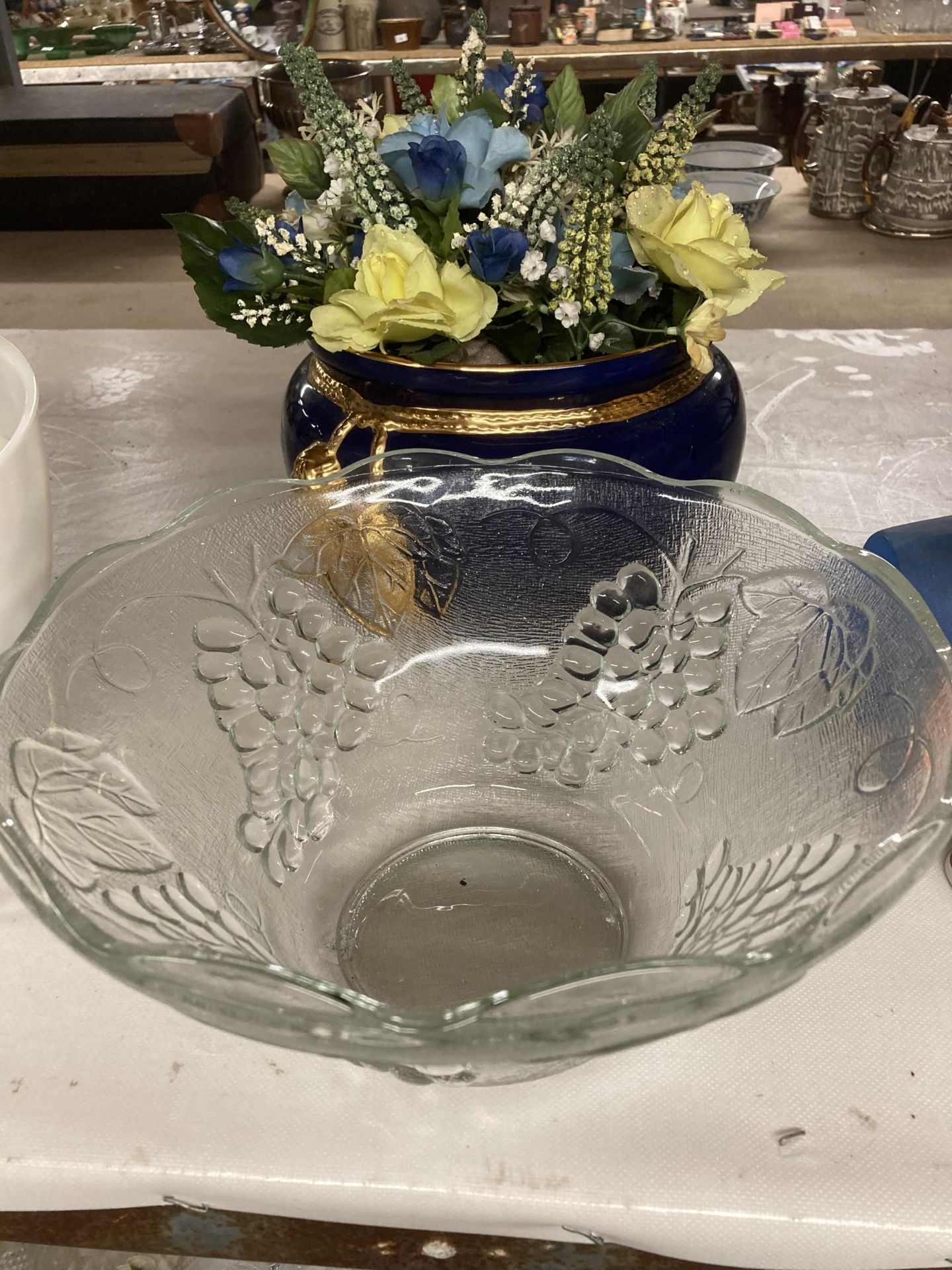 A LARGE GLASS BOWL WITH GRAPE AND VINE DECORATION AND A PLANTER CONTAINING DRIED FLOWERS