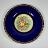 A ROYAL WORCESTER HAND PAINTED PORCELAIN PLATE, SIGNED J.PRICE DEPECITING FLOWERS AGAINST A COBALT