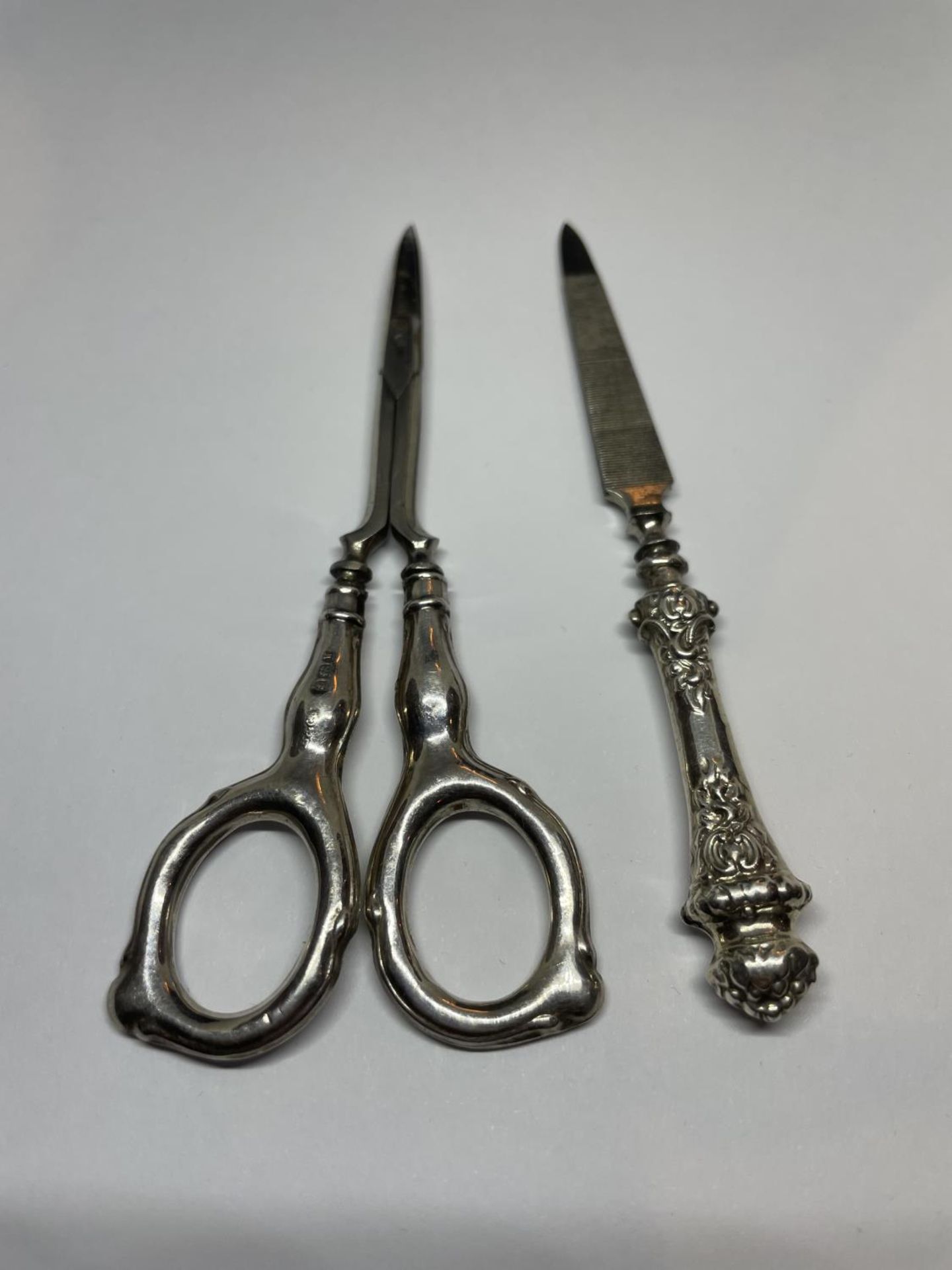 TWO SILVER HANDLED ITEMS TO INCLUDE A PAIR OF SISSORS AND A NAIL FILE