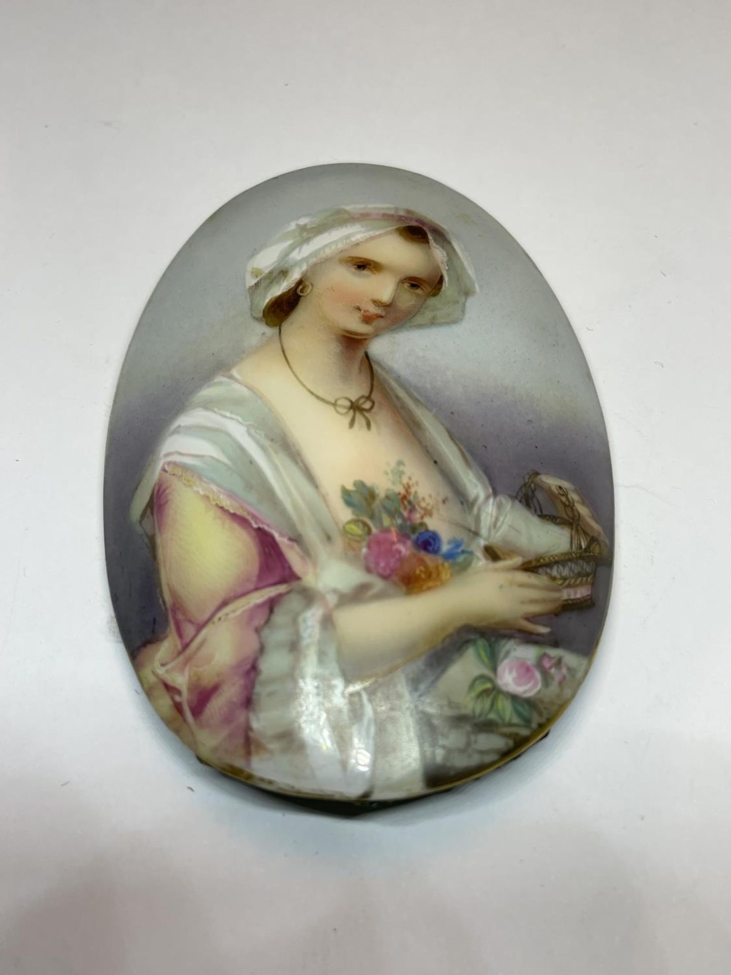 AN OVAL HAND PAINTED GLASS PLAQUE