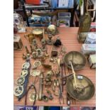 A LARGE ASSORTMENT OF BRASS ITEMS TO INCLUDE CANDLESTICKS, A GONG AND HORSE BRASSES ETC